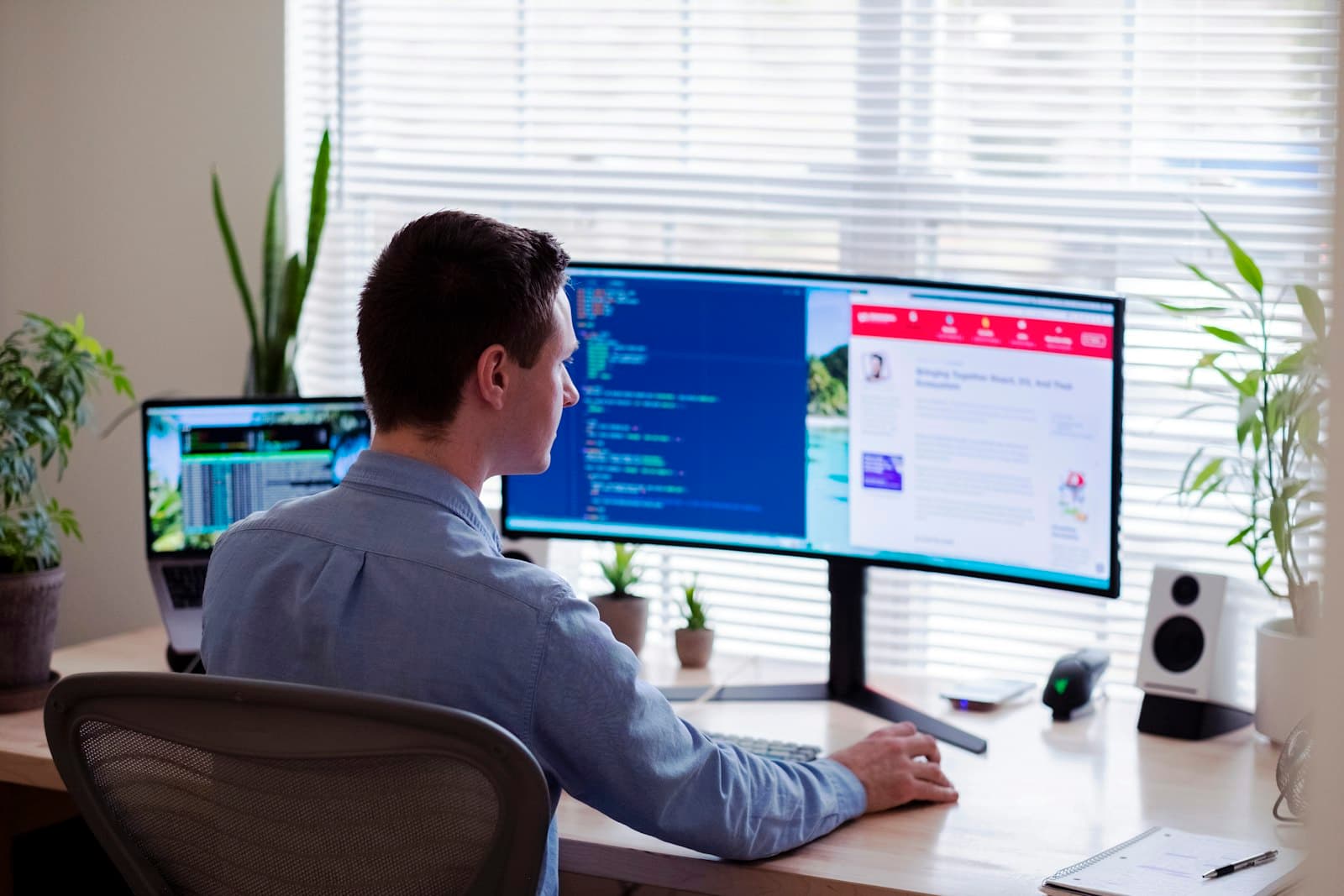 IT engineer reviewing system dashboards on a large monitor in a bright office.